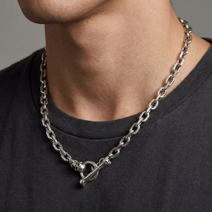 Silver skull bone toggle chain necklace worn by male model featuring chunky link chain with decorative skull clasp closure on dark gray t-shirt background