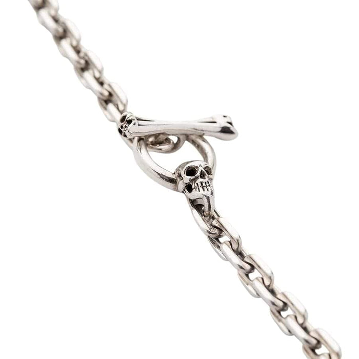 A close-up of the skull and crossbones T-bar clasp on the men's silver curb chain necklace.