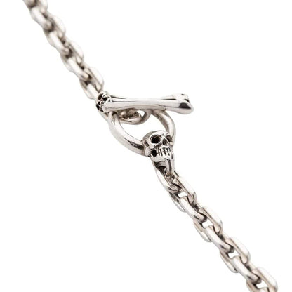 A close-up of the skull and crossbones T-bar clasp on the men's silver curb chain necklace.