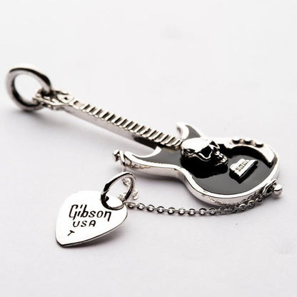 Angled detail of the black enamel guitar body featuring a 3D silver skull and attached Gibson USA engraved pick charm.