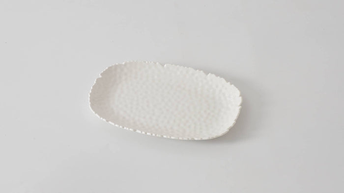 White ceramic plate with textured surface on a light gray background