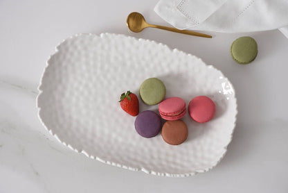 White textured platter with colorful macarons and a strawberry on a light background
