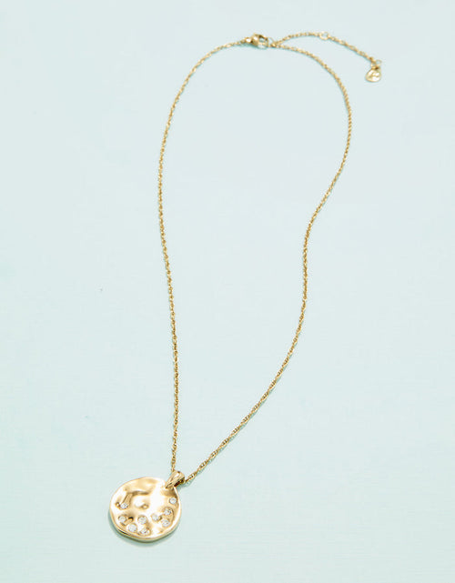 Gold necklace with a round pendant on a light blue background