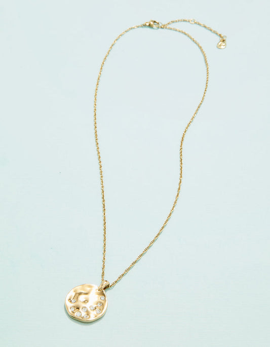 Gold necklace with a round pendant on a light blue background