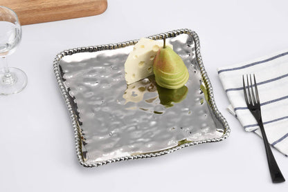 Metallic square tray with two pears on a white surface with a fork and napkin.