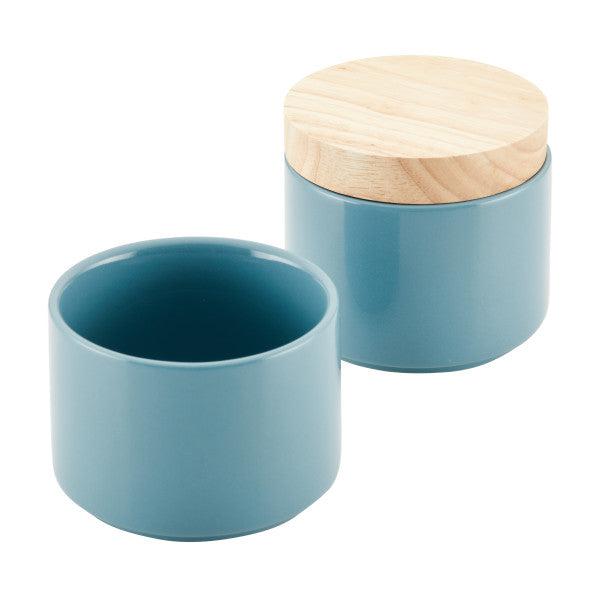 The Stacking Spice Box Set includes two ceramic jars in a soothing blue hue, with one featuring a wooden lid, perfect for use as spice containers or stacking options.
