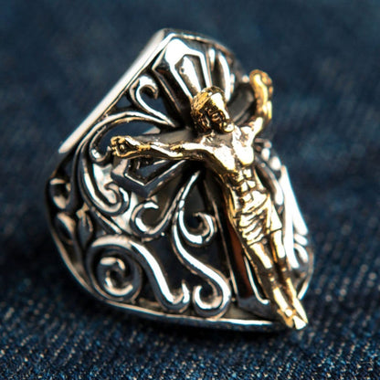 Handmade sterling silver crucifix ring with bronze Jesus figure photographed on denim fabric showing two-tone metal detail