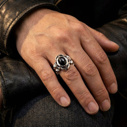 Tribal black onyx sterling silver ring worn on a man's finger, his hand resting on a worn leather jacket in moody light