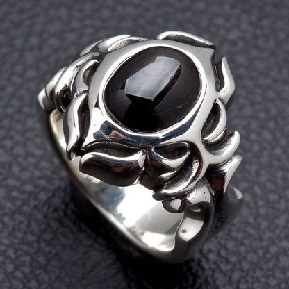 Angled view of the black onyx silver ring, the domed cabochon catching one highlight above flame-like tribal scrollwork