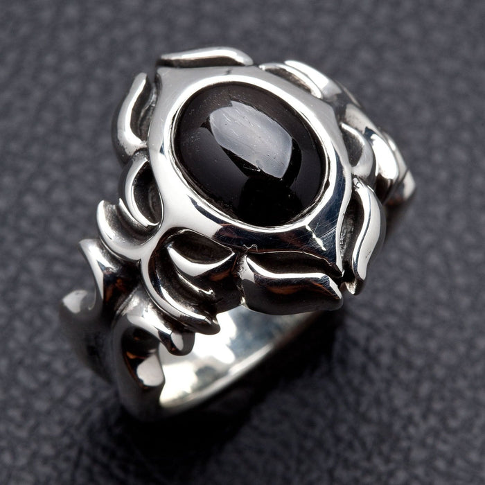 Left three-quarter view showing how the tribal silver carving wraps from the onyx setting down both shoulders of the band
