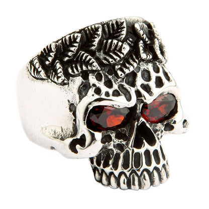 A large, hand-carved skull ring with a unique thorny crown and deep red gemstone eyes.