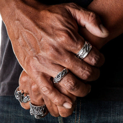 A man wearing the tribal silver band ring on his finger, styled with other biker rings.