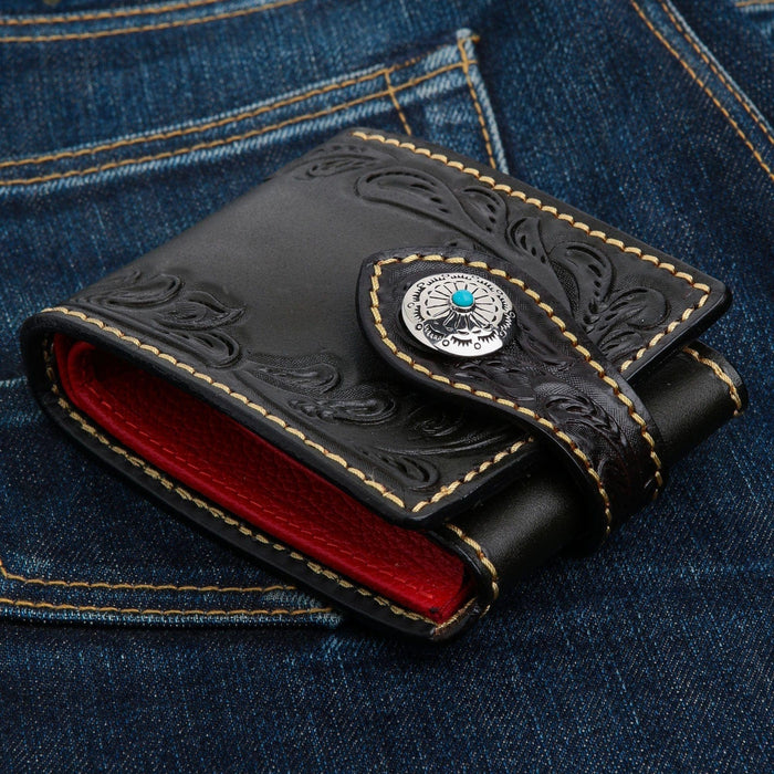 A classic Western-style biker wallet with a silver and turquoise snap, shown resting on a dark denim background.