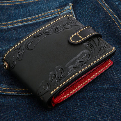 Tooled leaf and scroll work over black leather, a chain loop at the left and red lining showing at the edge.