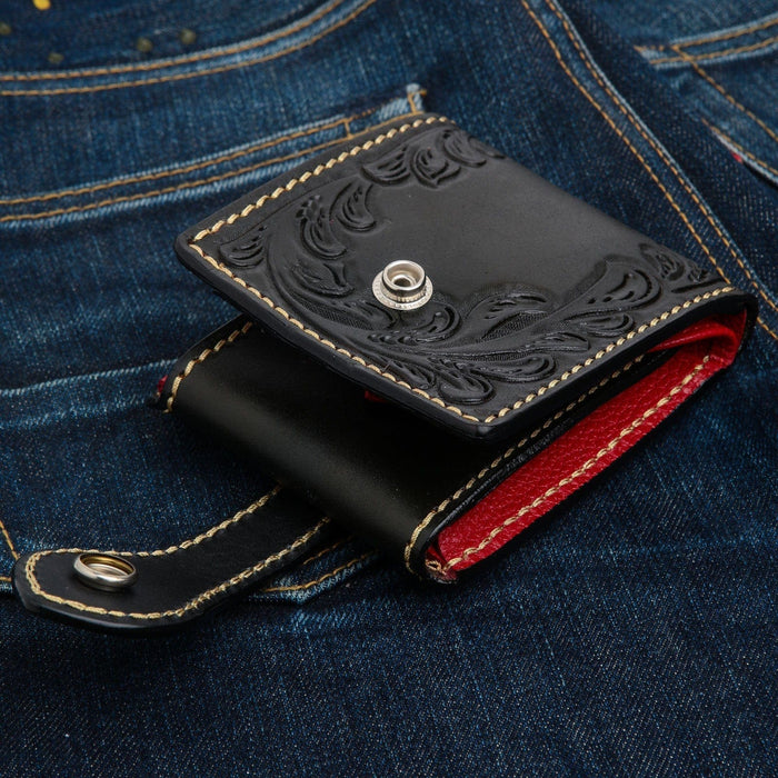 A unique, custom black and red leather wallet for bikers, with intricate, traditional floral tooling.