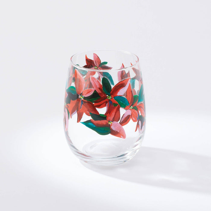 A stemless wine glass with a printed artwork of poinsettia leaves on a white background.