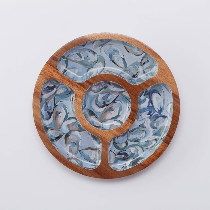 A round wooden snack tray with a pewter shell pattern in shades of blue and brown.